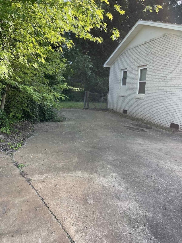 view of property exterior featuring brick siding, crawl space, and fence