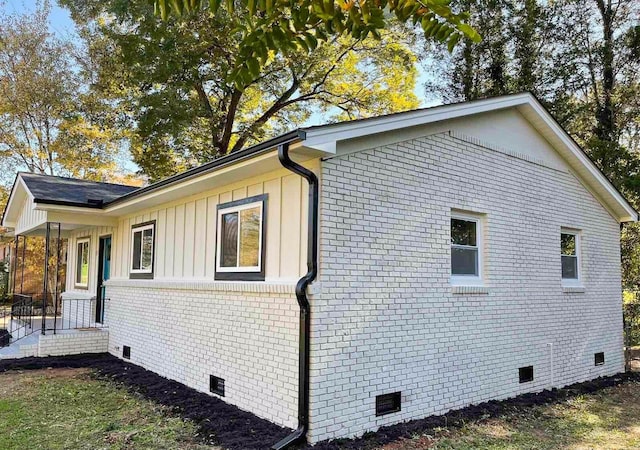 view of property exterior featuring brick siding, board and batten siding, and crawl space