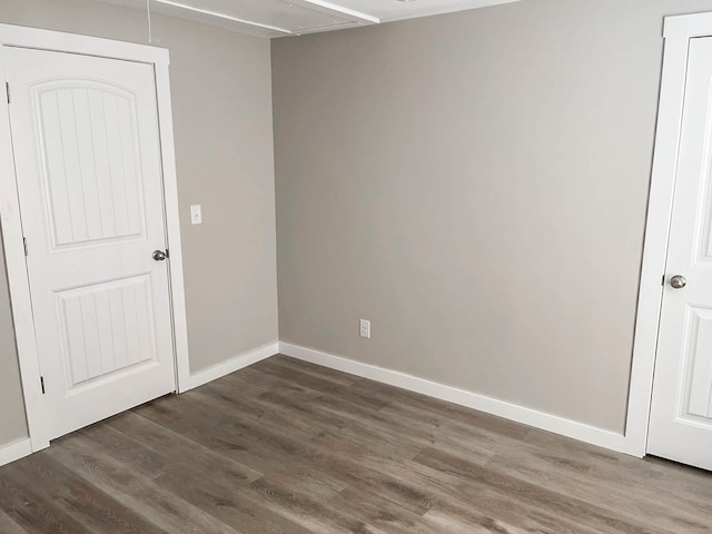 spare room featuring baseboards and wood finished floors