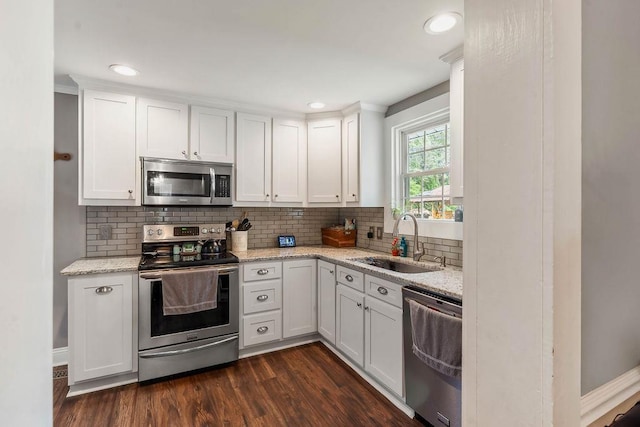 kitchen with decorative backsplash, appliances with stainless steel finishes, a sink, light stone counters, and white cabinetry