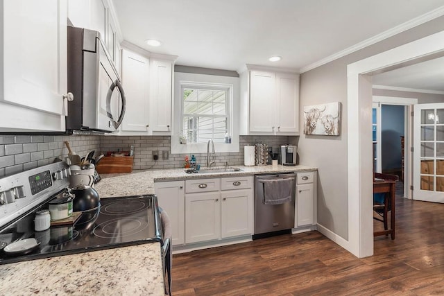 kitchen featuring crown molding, a sink, dark wood finished floors, stainless steel appliances, and decorative backsplash