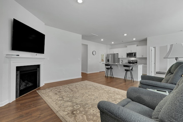 living room with recessed lighting, dark wood-style flooring, baseboards, and a fireplace