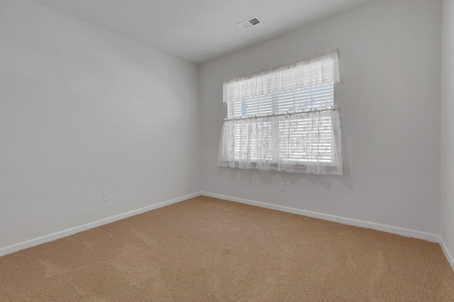carpeted spare room featuring baseboards and visible vents