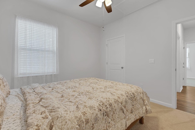 carpeted bedroom with ceiling fan, baseboards, and attic access