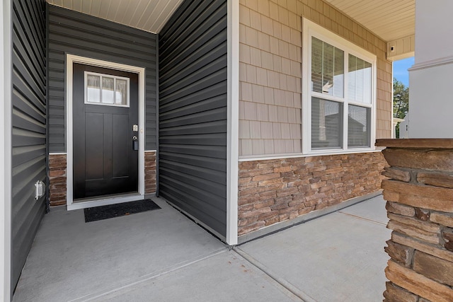 doorway to property with a porch and stone siding