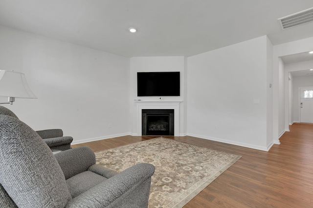 living area with baseboards, visible vents, wood finished floors, and a fireplace