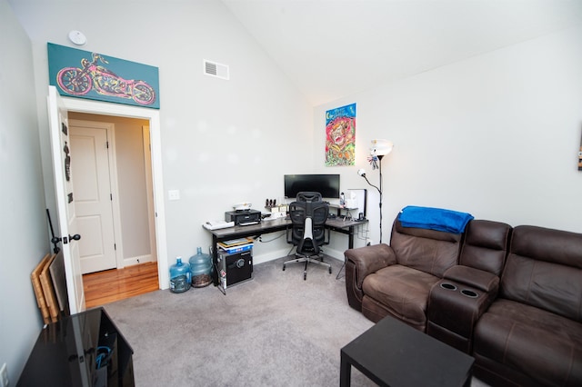 carpeted office with high vaulted ceiling, visible vents, and baseboards