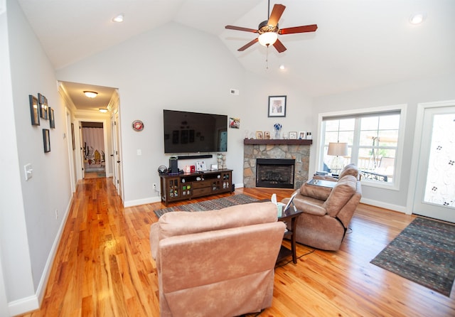 living area featuring light wood-style floors, a fireplace, high vaulted ceiling, a ceiling fan, and baseboards