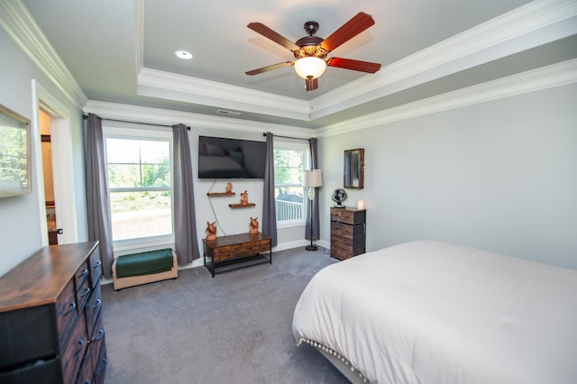 bedroom featuring a ceiling fan, a tray ceiling, ornamental molding, and dark colored carpet