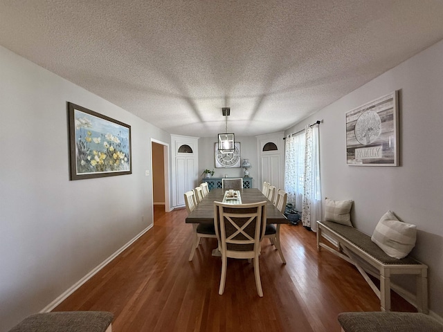 dining space featuring baseboards, a textured ceiling, and dark wood finished floors