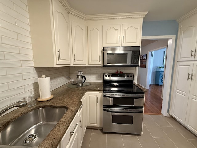 kitchen with backsplash, a sink, white cabinets, stainless steel appliances, and light tile patterned flooring