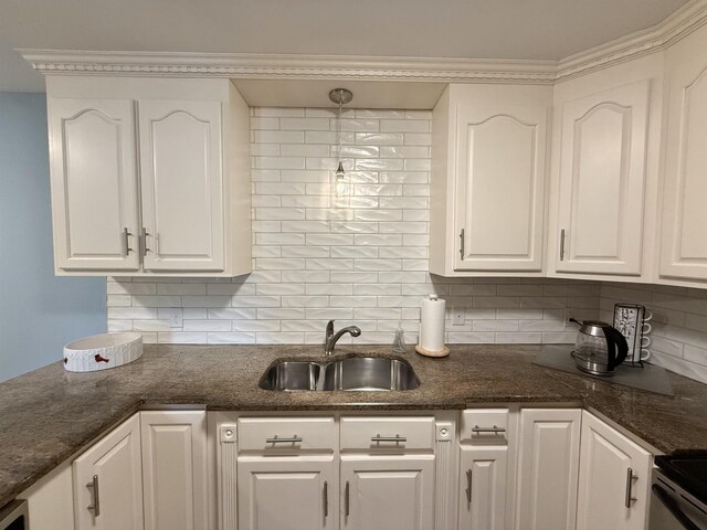 kitchen with electric stove, white cabinetry, tasteful backsplash, a sink, and dark stone countertops