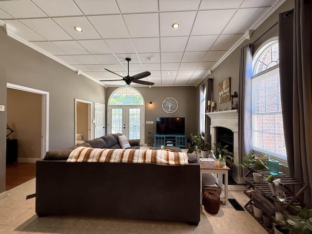 living room featuring crown molding, a ceiling fan, plenty of natural light, and a fireplace