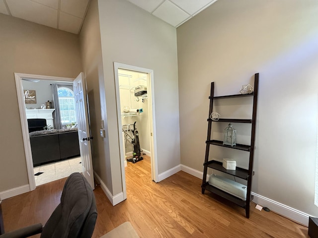 home office featuring a fireplace, baseboards, a paneled ceiling, and light wood-style floors