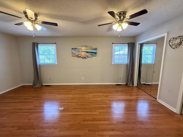 spare room with baseboards, a ceiling fan, a textured ceiling, and wood finished floors