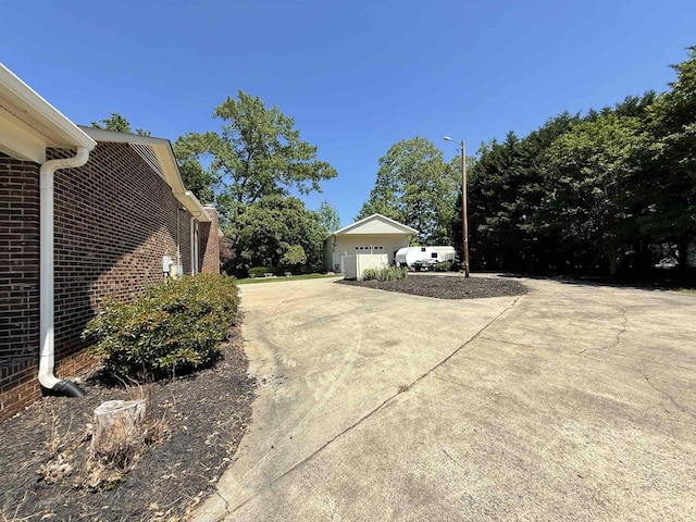 view of home's exterior with brick siding, a garage, and concrete driveway