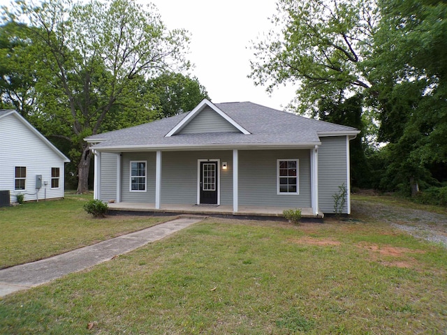 bungalow-style home featuring covered porch, a shingled roof, central AC unit, and a front lawn