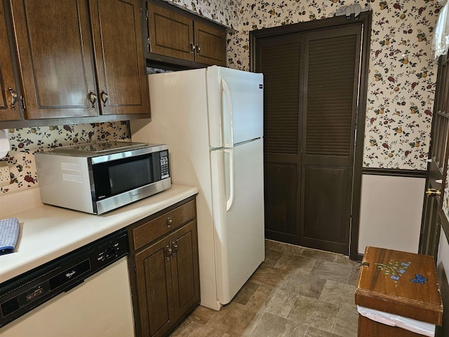 kitchen with light countertops, dark brown cabinetry, white appliances, and wallpapered walls