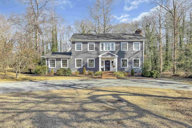 colonial inspired home with a front yard and a chimney