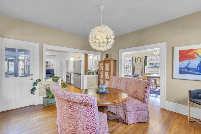 dining area featuring baseboards, an inviting chandelier, and light wood-type flooring