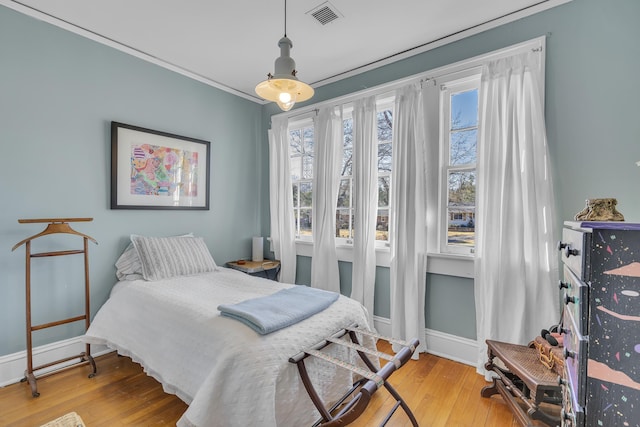 bedroom with visible vents, ornamental molding, baseboards, and hardwood / wood-style flooring