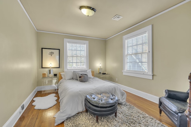 bedroom featuring crown molding, baseboards, wood finished floors, and visible vents