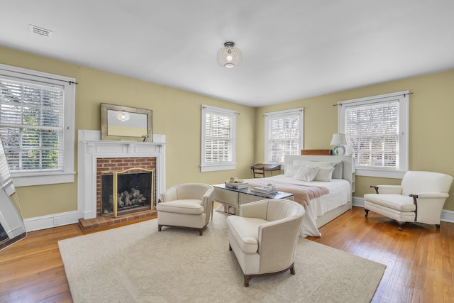 bedroom with multiple windows, a fireplace, hardwood / wood-style floors, and visible vents