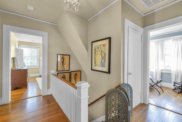 hallway featuring crown molding, an upstairs landing, an inviting chandelier, and hardwood / wood-style floors