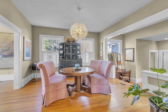 dining space with visible vents, baseboards, an inviting chandelier, and light wood finished floors