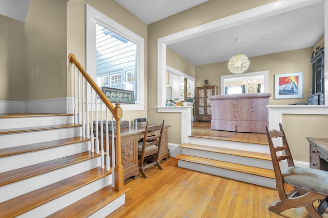 stairway with an inviting chandelier and wood-type flooring