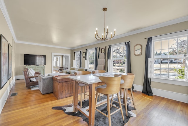 dining area featuring a chandelier, visible vents, ornamental molding, and light wood-type flooring
