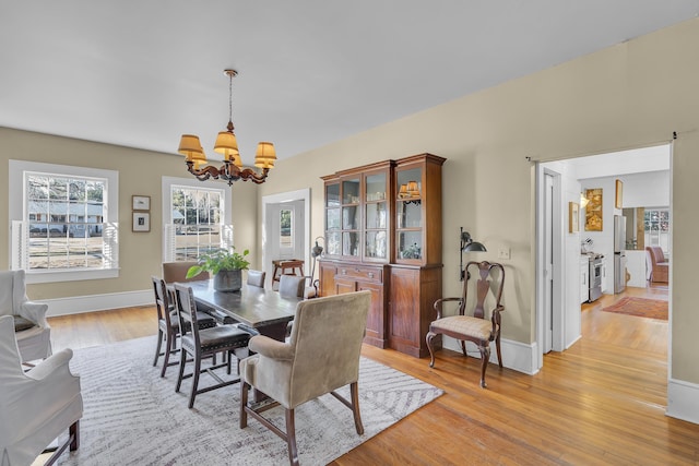 dining room featuring baseboards, an inviting chandelier, and light wood-style floors