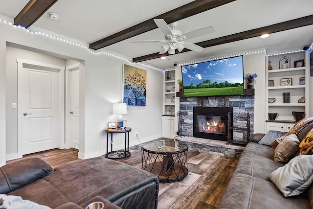 living room featuring baseboards, beamed ceiling, a stone fireplace, and wood finished floors