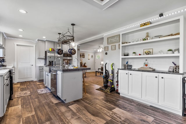 kitchen with dark wood-style flooring, dark countertops, appliances with stainless steel finishes, a sink, and gray cabinets