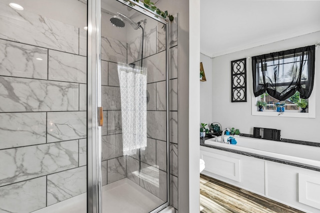 full bathroom featuring wood finished floors, a bath, and a shower stall