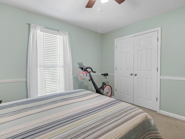 bedroom with a textured ceiling, carpet, a ceiling fan, baseboards, and a closet