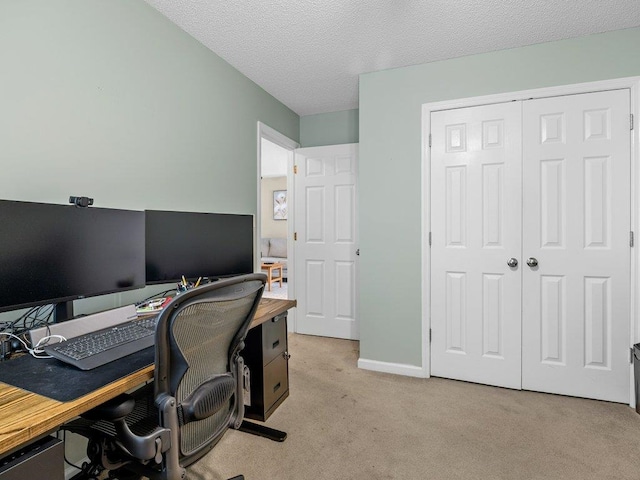 office space with a textured ceiling, light colored carpet, and baseboards