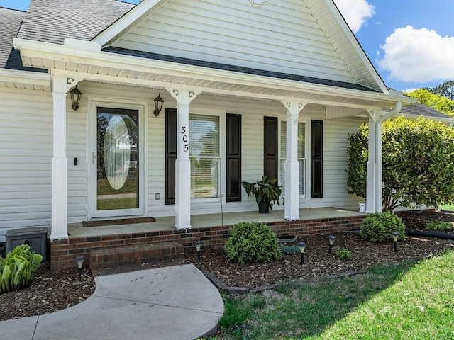 property entrance featuring roof with shingles and a porch