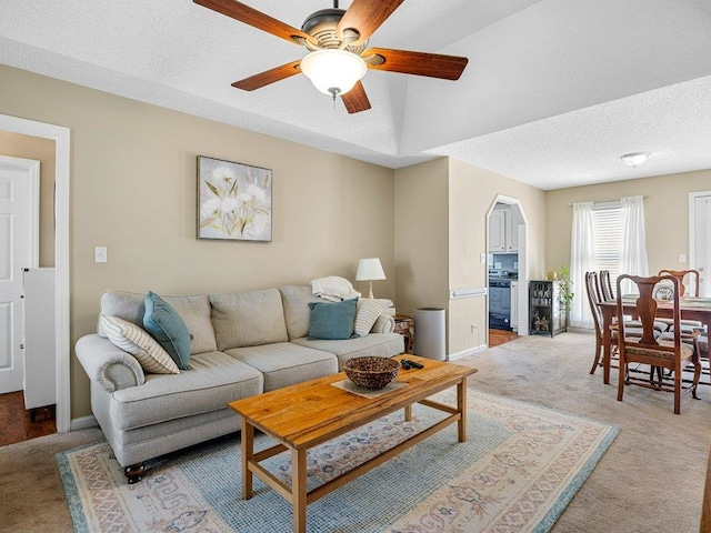living room with arched walkways, baseboards, a ceiling fan, and light colored carpet