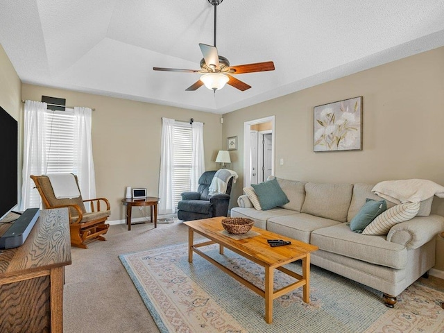 living room with a ceiling fan, baseboards, and light colored carpet