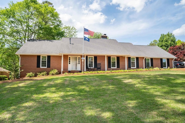 ranch-style house with a chimney, a front yard, and brick siding
