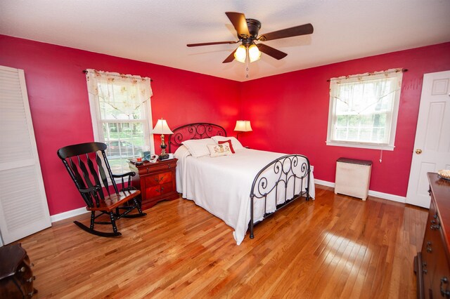 bedroom featuring a ceiling fan, baseboards, and light wood-style floors