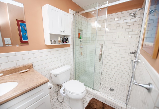 full bath with vanity, tile walls, a stall shower, and toilet