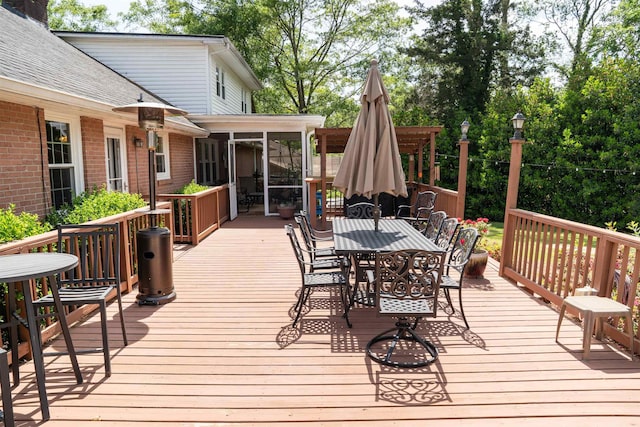 wooden terrace with outdoor dining area and a sunroom