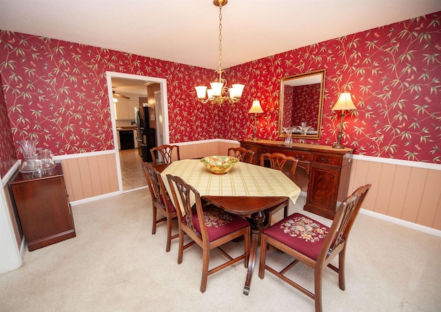 dining space with wallpapered walls, carpet, and a wainscoted wall
