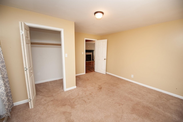 unfurnished bedroom featuring baseboards, light carpet, and a closet