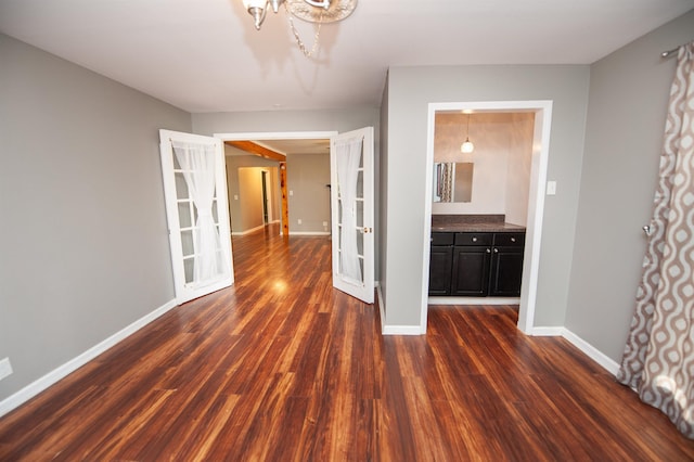 interior space featuring baseboards, a chandelier, and dark wood-style floors