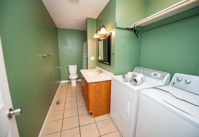 washroom with washer and dryer, light tile patterned flooring, laundry area, a sink, and baseboards