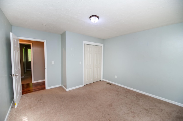 unfurnished bedroom with carpet flooring, baseboards, visible vents, and a closet