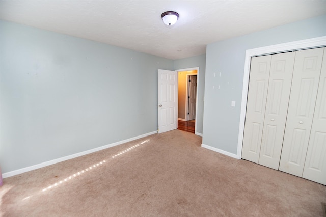 unfurnished bedroom featuring carpet flooring, baseboards, and a closet